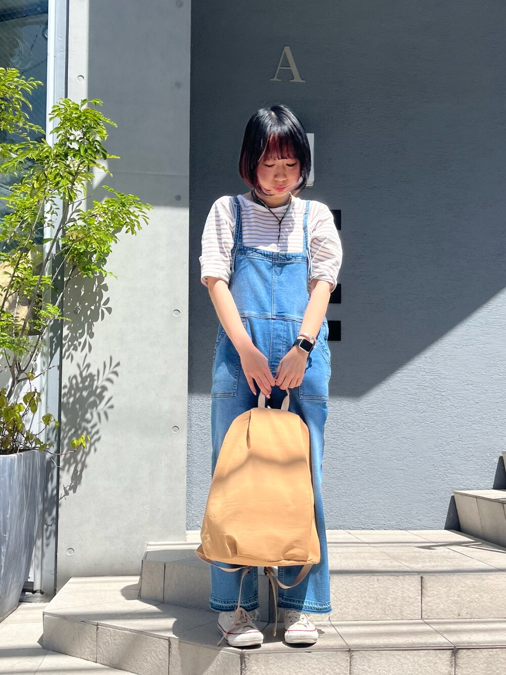 ベージュ系のバックパック/リュック、ホワイト系のスニーカーを着用したレディースの春コーディネートの2枚目の写真