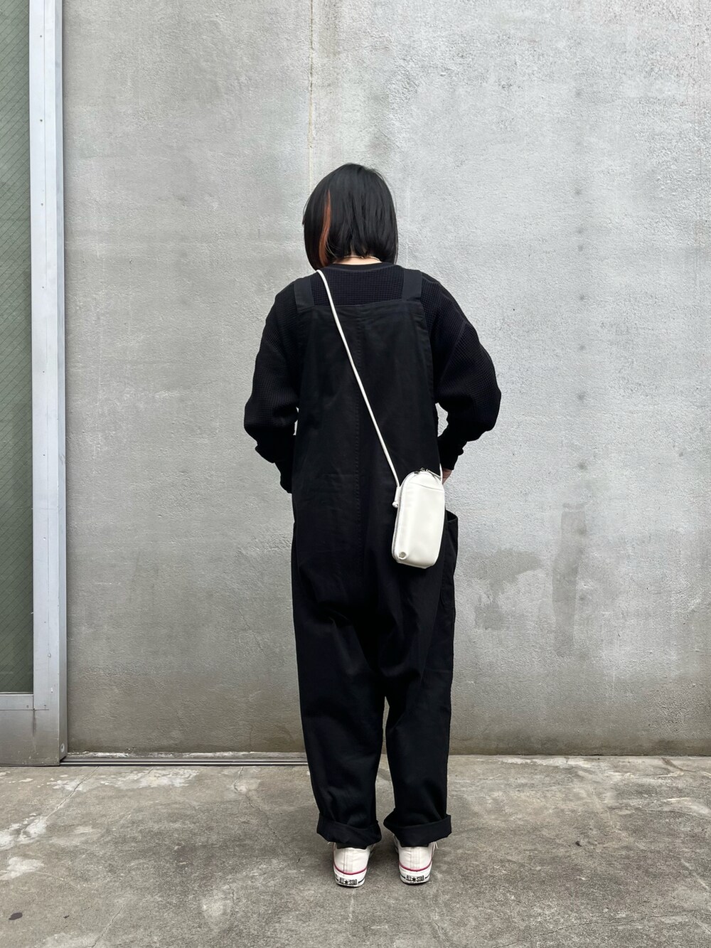 ホワイト系のショルダーバッグ、ブラック系のトップス、ブラック系のサロペット/オーバーオールを着用したレディースの冬コーディネートの2枚目の写真