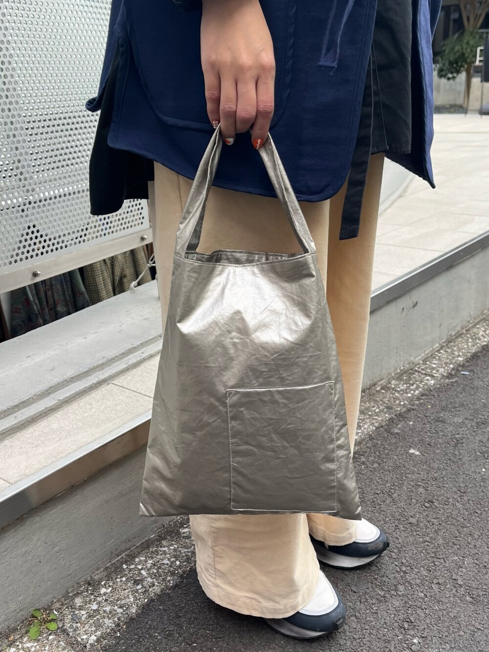 ブルー系のベスト、ゴールド系のトートバッグ、ホワイト系のスニーカーを着用したレディースの冬コーディネートの2枚目の写真