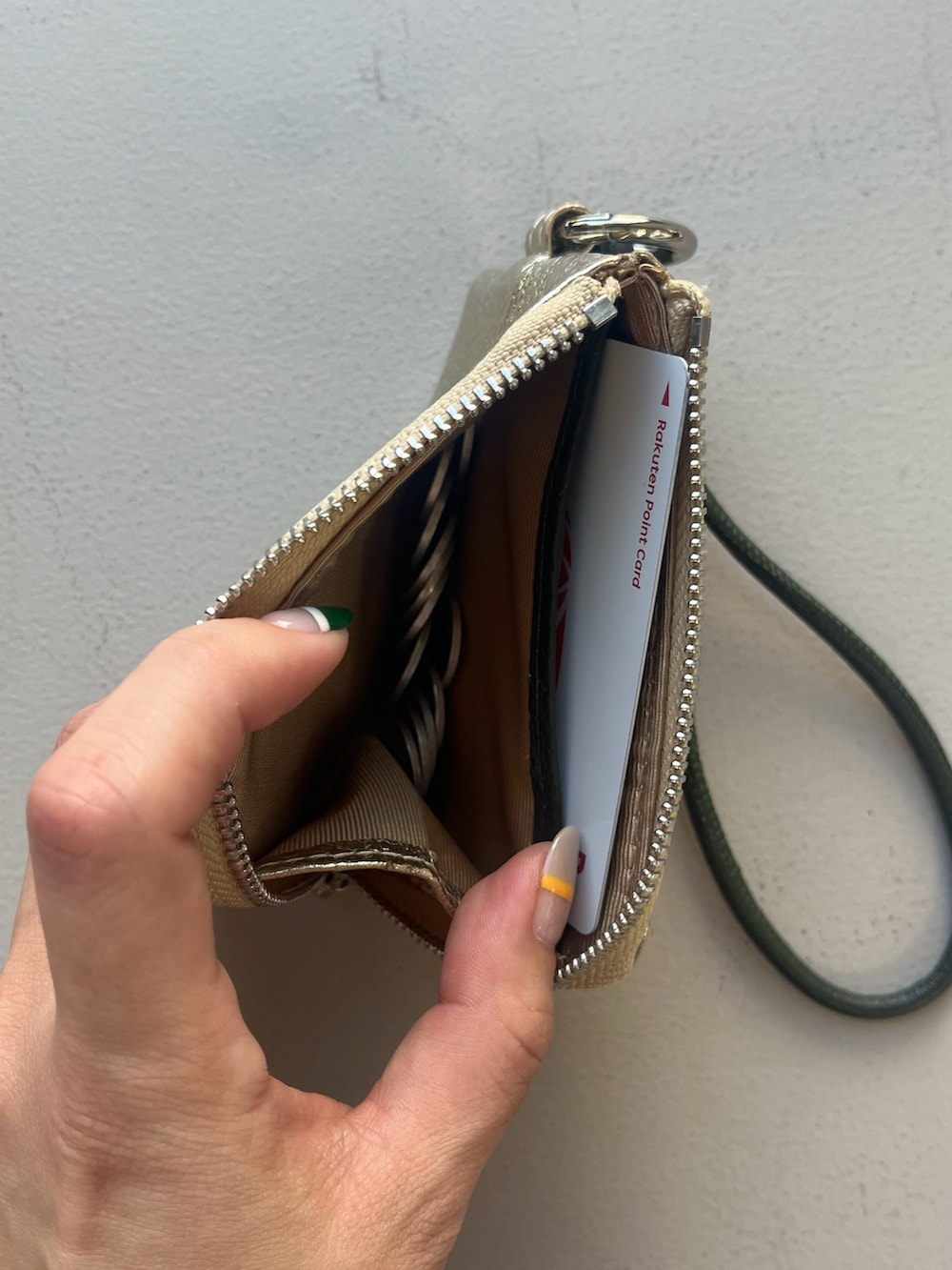 オレンジ系のキーホルダー、ベージュ系の財布、ピンク系のヘアオイル/ヘアミルクを着用したレディースの春コーディネートの3枚目の写真