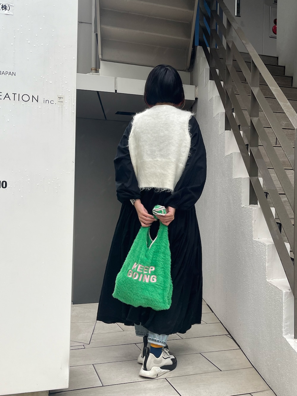 ホワイト系のスニーカー、グリーン系のトートバッグ、ブラック系のワンピースを着用したレディースの秋コーディネートの2枚目の写真