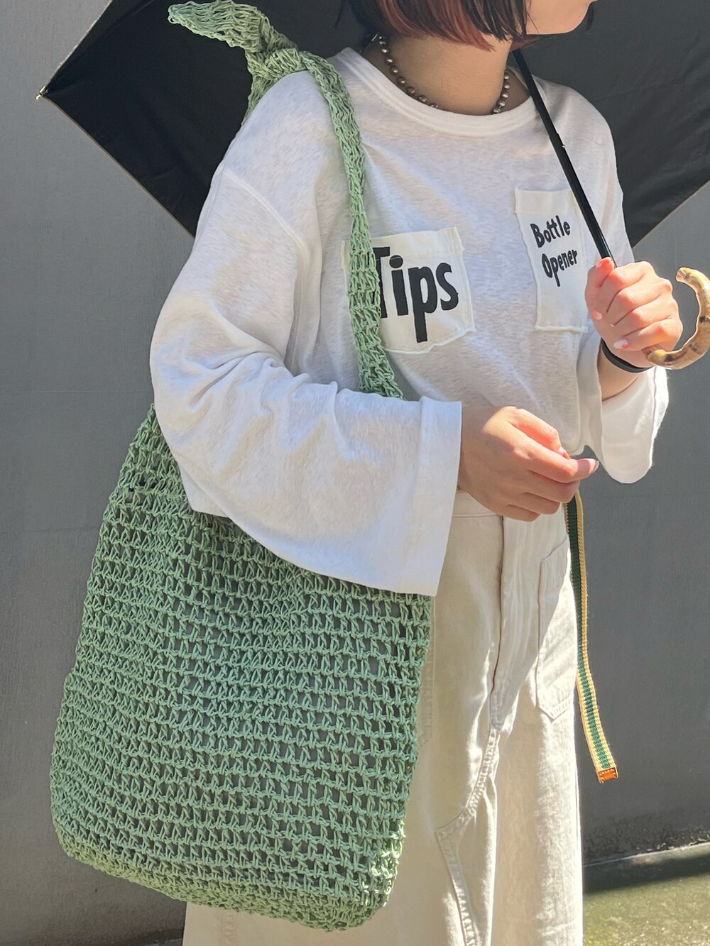 ホワイト系のスニーカー、グリーン系のショルダーバッグ、ベージュ系のスカートを着用したレディースの春コーディネートの3枚目の写真