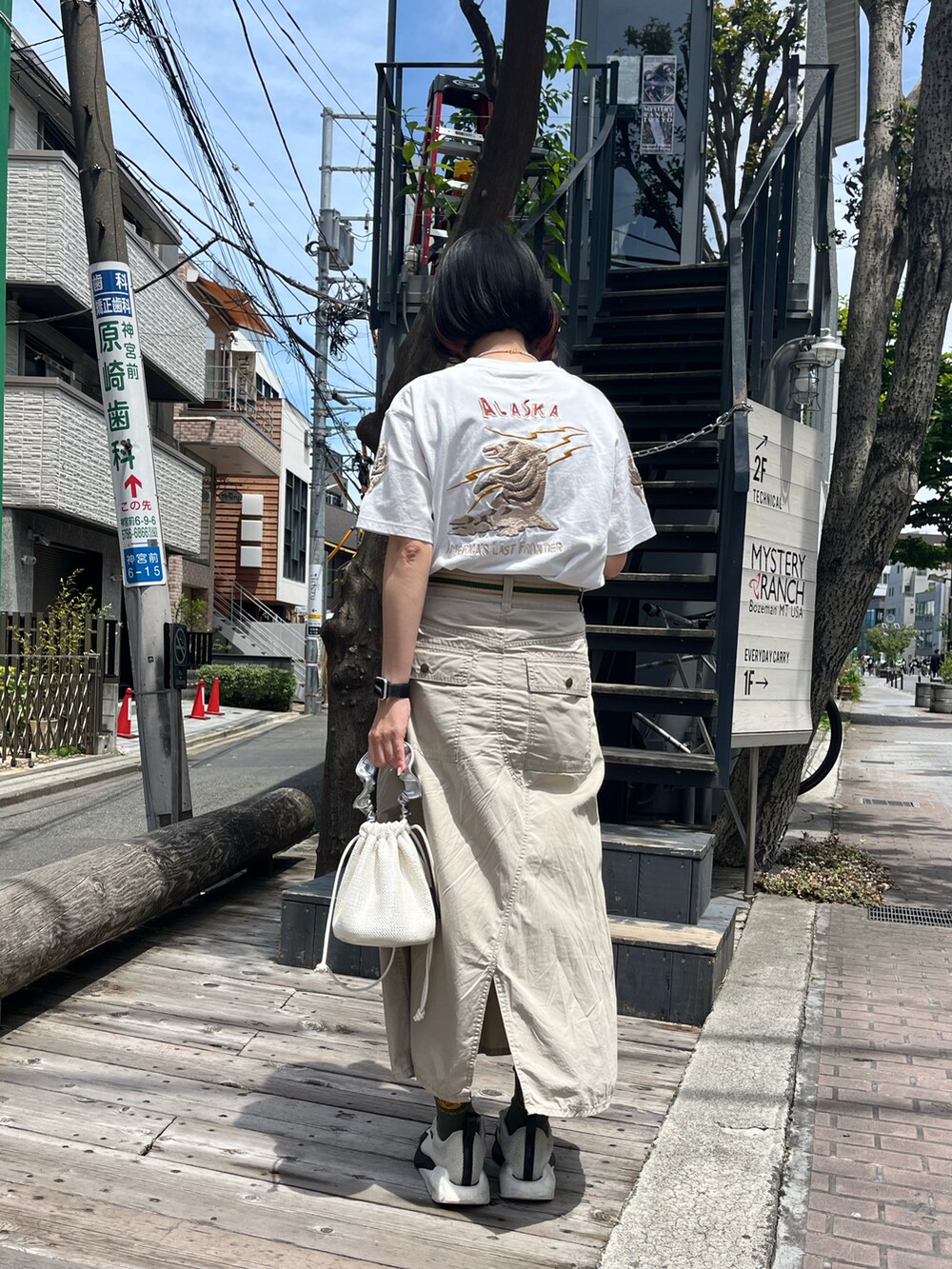 ホワイト系のスニーカー、ベージュ系のスカート、ホワイト系のトートバッグを着用したレディースの春コーディネートの2枚目の写真