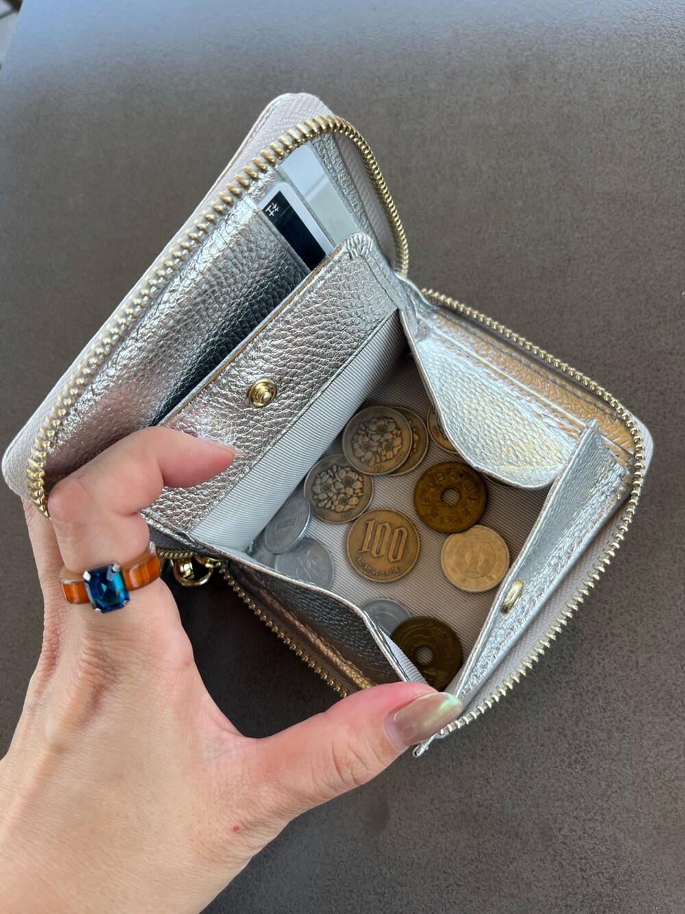 シルバー系のショルダーバッグ、グレー系のヘッドフォン/イヤホン、シルバー系の財布を着用したレディースの夏コーディネートの3枚目の写真