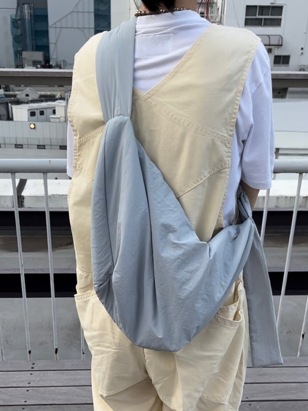 ベージュ系のオールインワン・サロペット、ホワイト系のスニーカー、ブルー系のショルダーバッグを着用したレディースの夏コーディネートの3枚目の写真