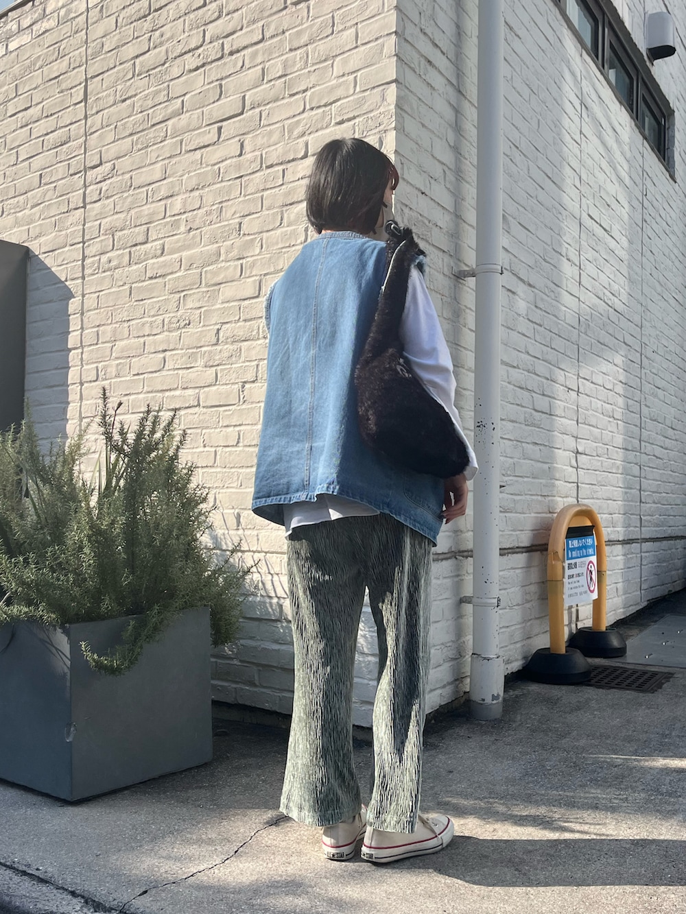 ブラック系のトートバッグ、ブルー系のベスト、ホワイト系のTシャツ/カットソーを着用したレディースの秋コーディネートの2枚目の写真