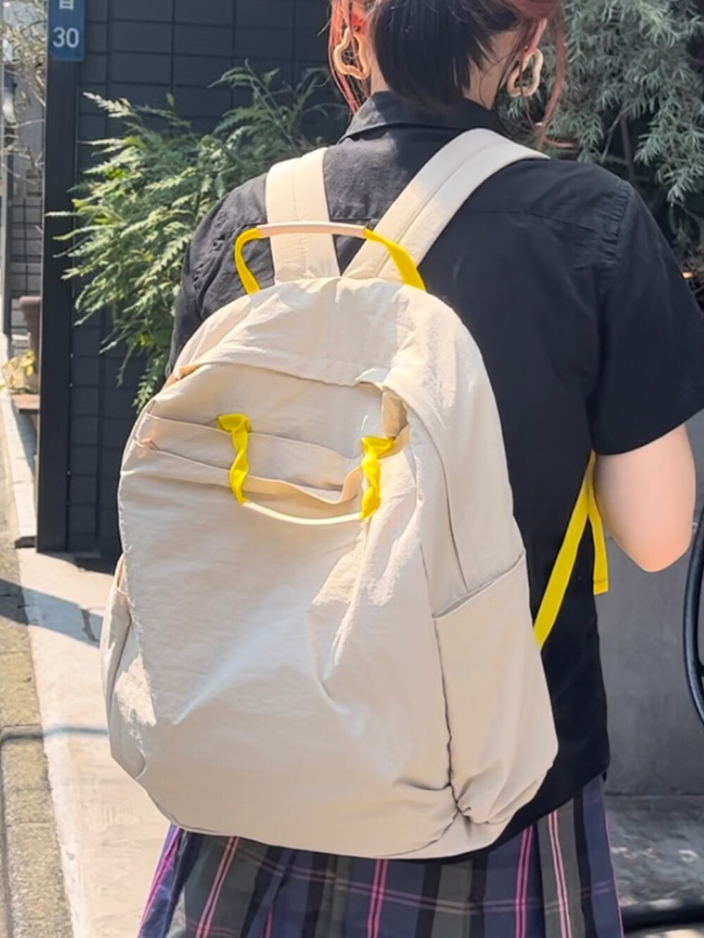 ベージュ系のバックパック/リュック、ホワイト系のスニーカー、ブラック系のシャツ/ブラウスを着用したレディースの夏コーディネートの4枚目の写真