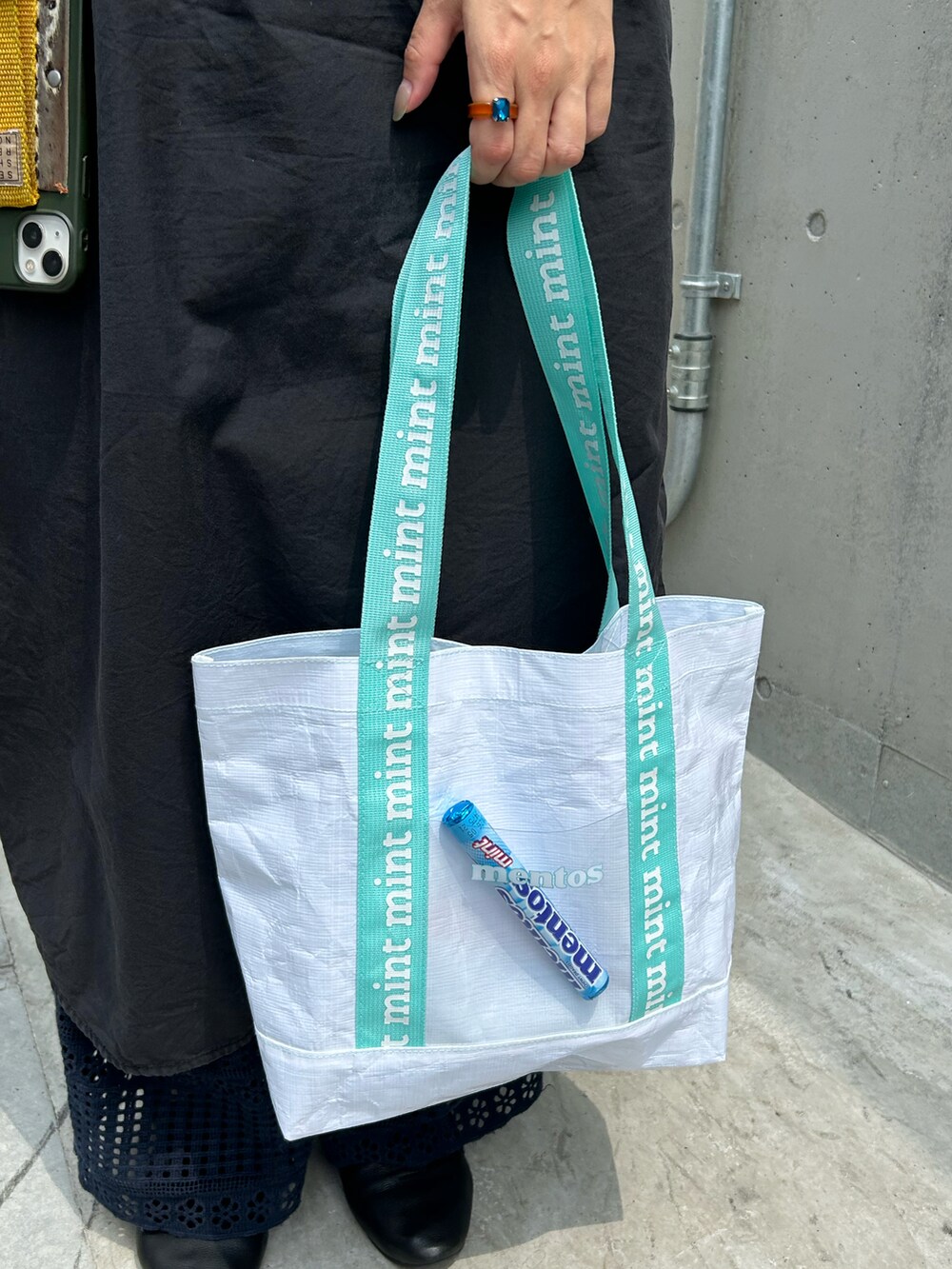 ブラック系のドレスシューズ、ブルー系のトートバッグ、ブラック系のワンピースを着用したレディースの夏コーディネートの2枚目の写真