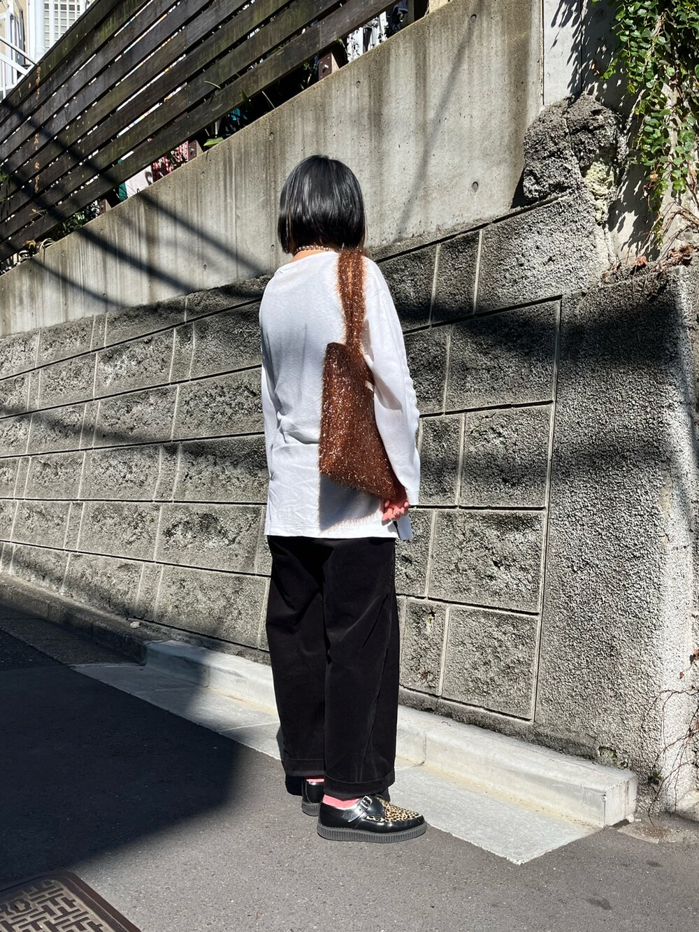 ブラウン系のトートバッグ、ホワイト系のTシャツ/カットソーを着用したレディースの秋コーディネートの2枚目の写真