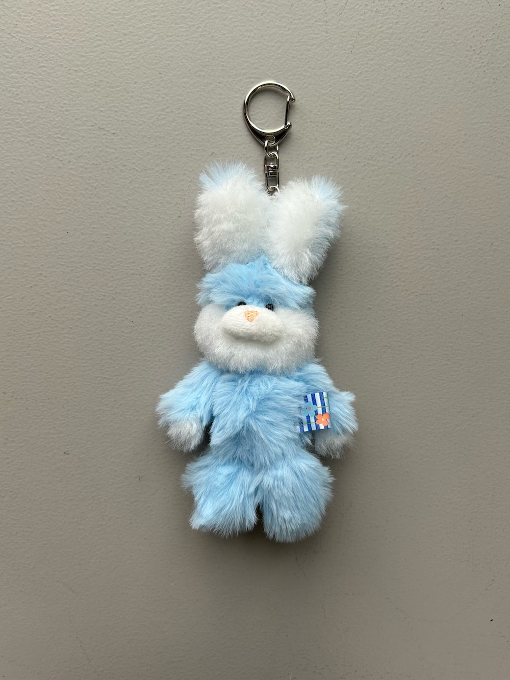 オレンジ系のポーチ、ゴールド系のパスケース、ブルー系のチャームを着用したレディースの春コーディネートの2枚目の写真