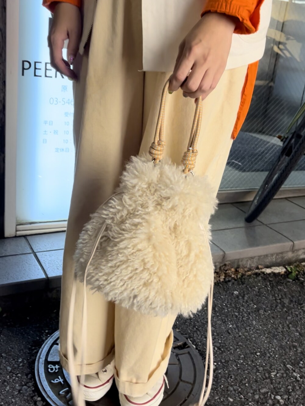 ホワイト系のトートバッグ、ホワイト系のスニーカー、ホワイト系のベストを着用したレディースの秋コーディネートの3枚目の写真