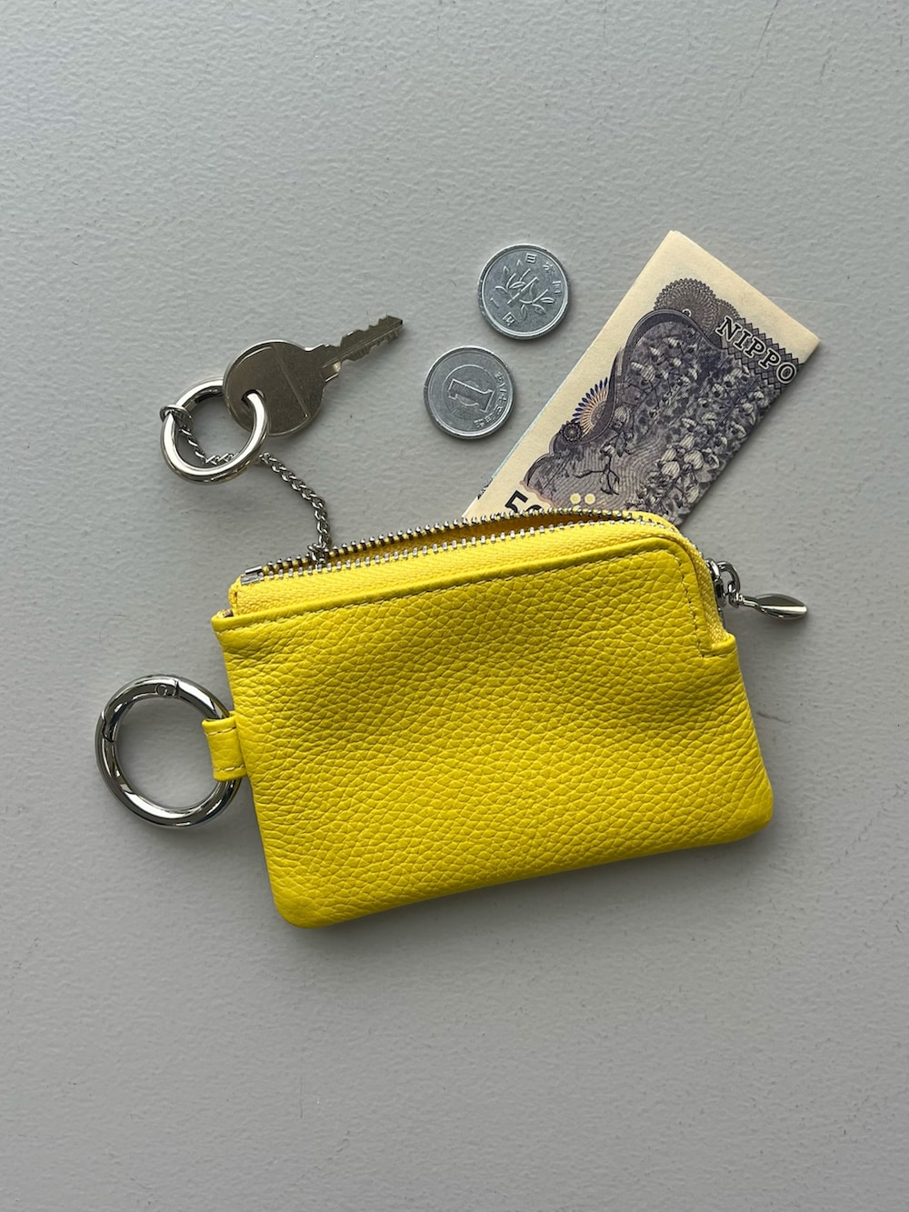 ホワイト系のポーチ、グリーン系の生活家電、イエロー系のパスケースを着用したレディースの春コーディネートの4枚目の写真
