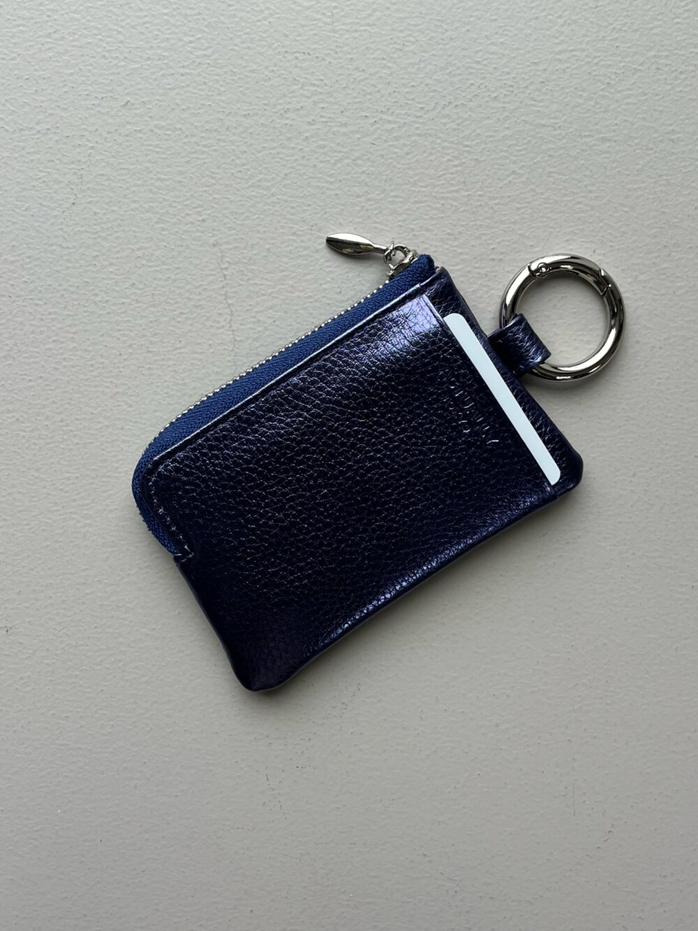 シルバー系のチャーム、ブルー系のパスケース、グリーン系のポーチを着用したレディースの冬コーディネートの2枚目の写真