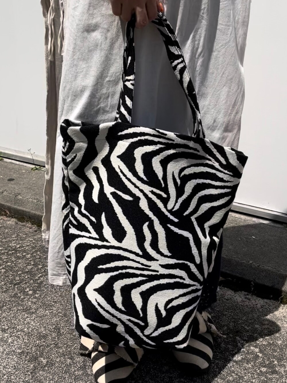 ホワイト系のトップス、ブルー系のパンツ、その他のトートバッグを着用したレディースの夏コーディネートの2枚目の写真