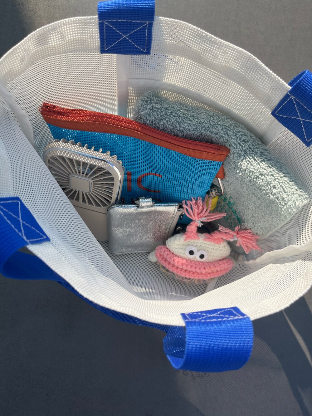 ホワイト系のトートバッグ、ブルー系のポーチ、シルバー系の財布を着用したレディースの夏コーディネートの2枚目の写真