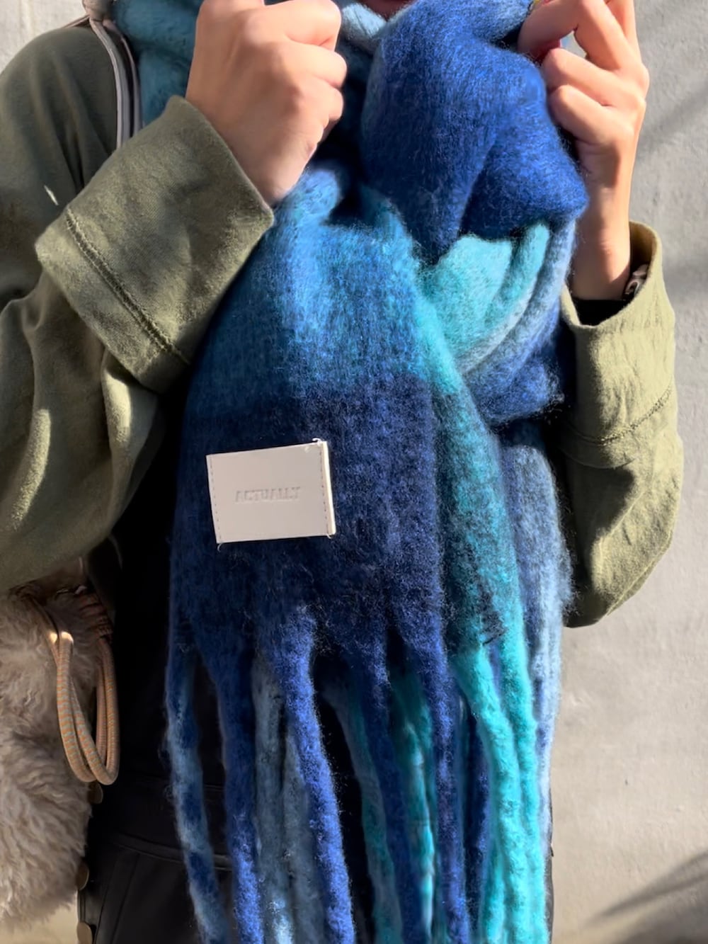 ホワイト系のトートバッグ、ブラック系のローファー、ブルー系のストール/ショールを着用したレディースの秋コーディネートの3枚目の写真