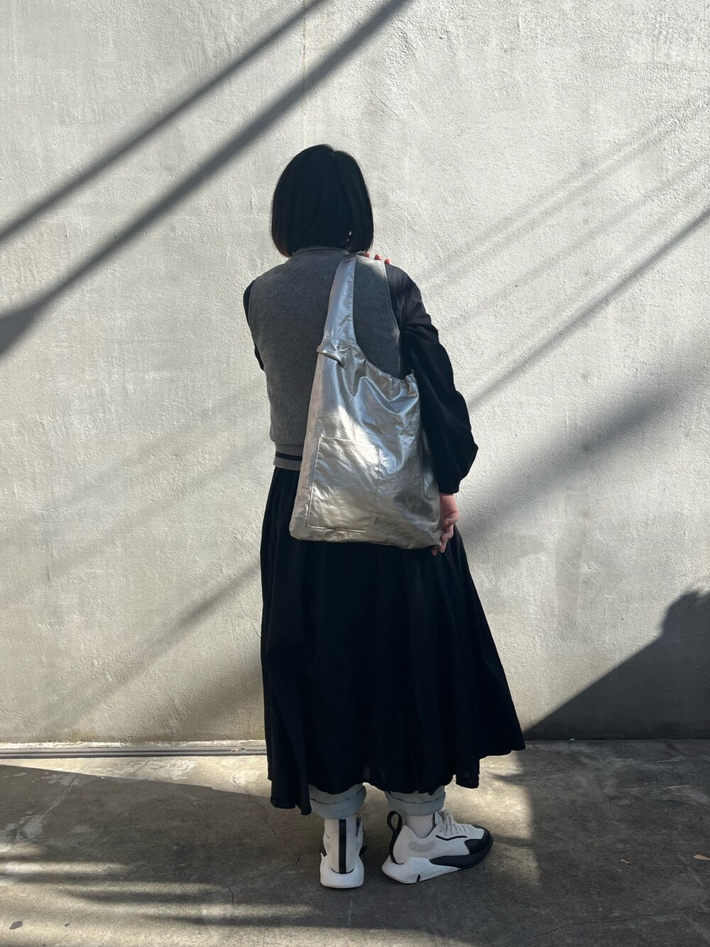 ゴールド系のトートバッグ、ホワイト系のスニーカーを着用したレディースの秋コーディネートの2枚目の写真