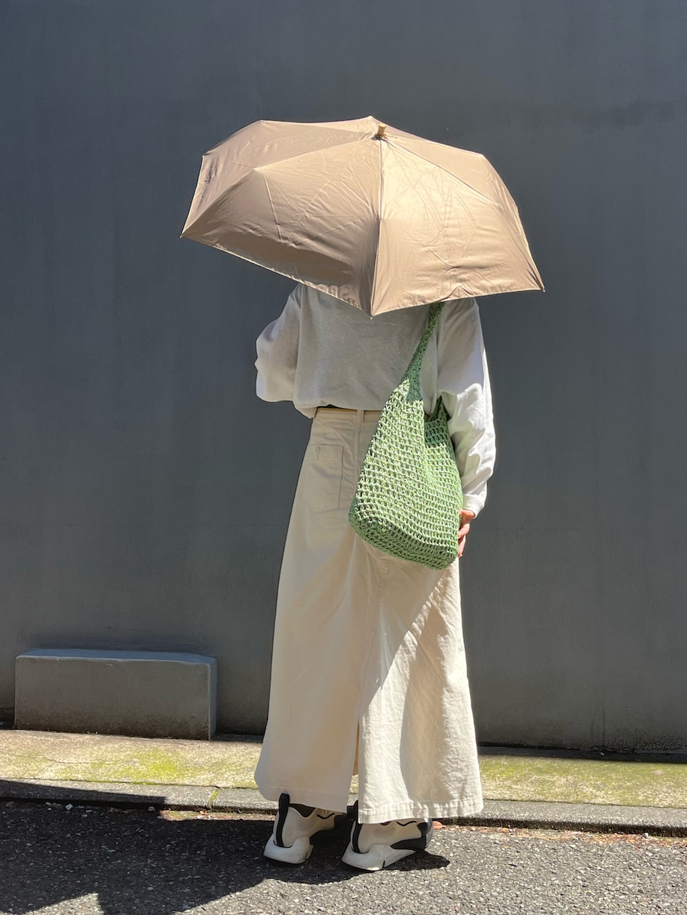 ホワイト系のスニーカー、グリーン系のショルダーバッグ、ベージュ系のスカートを着用したレディースの春コーディネートの2枚目の写真