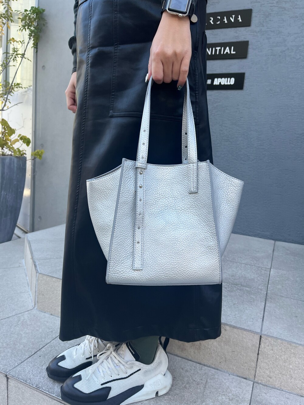 シルバー系のトートバッグ、ブラック系のTシャツ/カットソー、ブラック系のジャンパースカートを着用したレディースの冬コーディネートの3枚目の写真