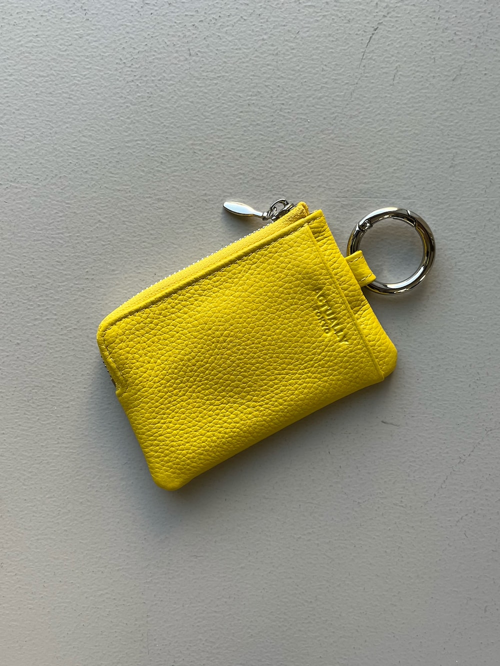 ピンク系のポーチ、イエロー系のパスケース、グリーン系のハンドケア/ハンドクリームを着用したレディースの春コーディネートの4枚目の写真