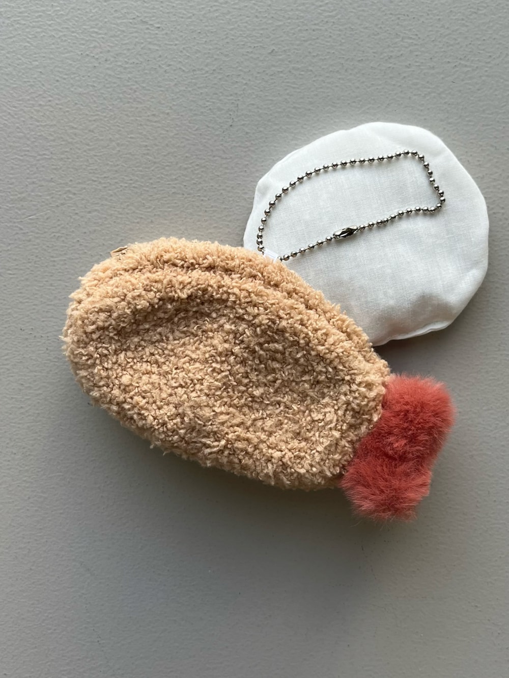 ホワイト系のポーチ、シルバー系の財布、イエロー系のインテリア雑貨を着用したレディースの冬コーディネートの3枚目の写真