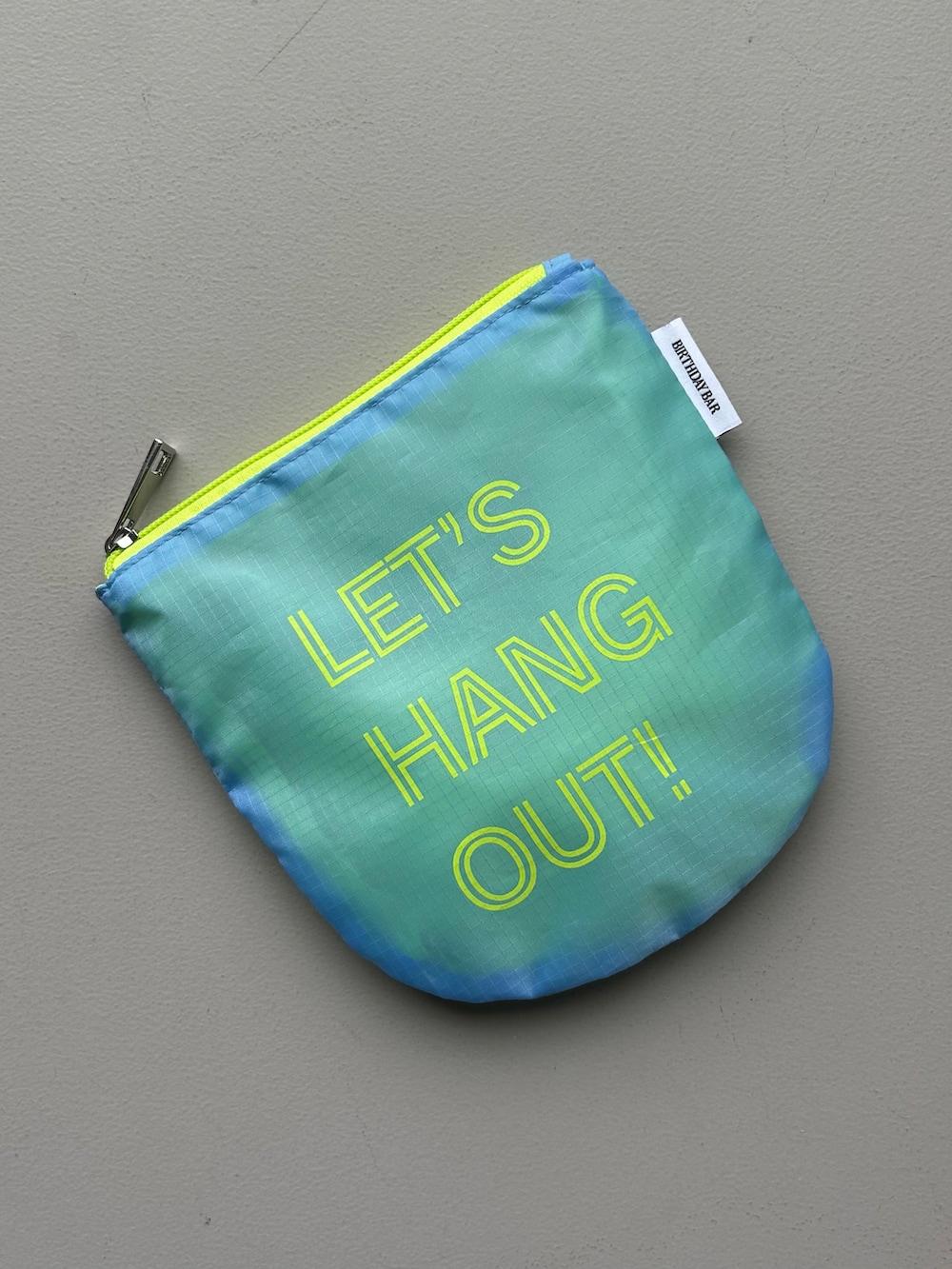 ブルー系のポーチ、ベージュ系の名刺入れ、ホワイト系のチャームを着用したレディースの春コーディネートの3枚目の写真