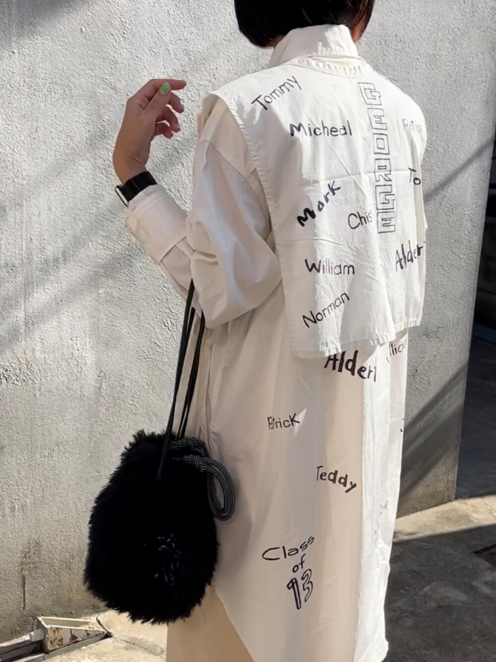 ブラック系のトートバッグ、ホワイト系のベスト、ホワイト系のワンピースを着用したレディースの秋コーディネートの2枚目の写真