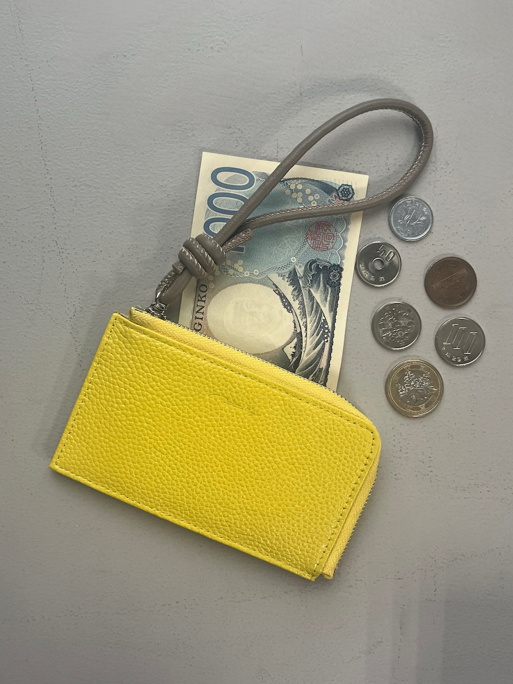 ホワイト系のポーチ、イエロー系の財布、オレンジ系のチャームを着用したレディースの春コーディネートの2枚目の写真