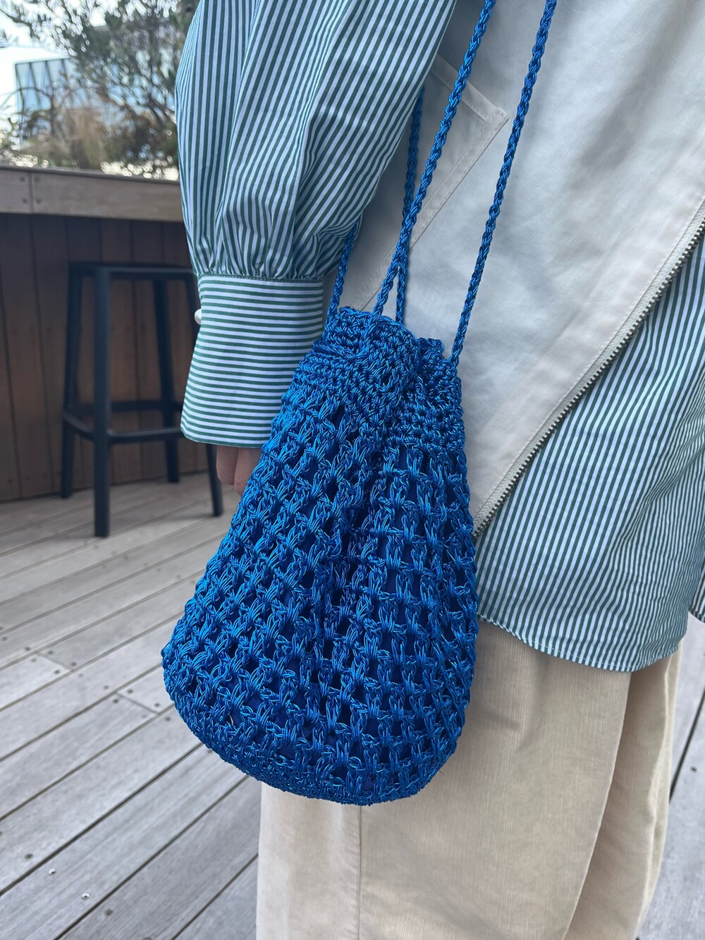 ブルー系のショルダーバッグ、ホワイト系のスニーカー、ホワイト系のベストを着用したレディースの冬コーディネートの3枚目の写真