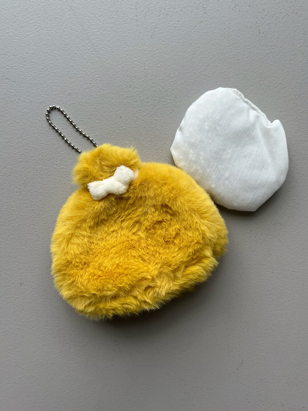 ゴールド系のパスケース、ホワイト系のチャーム、イエロー系のインテリア雑貨を着用したレディースの冬コーディネートの2枚目の写真