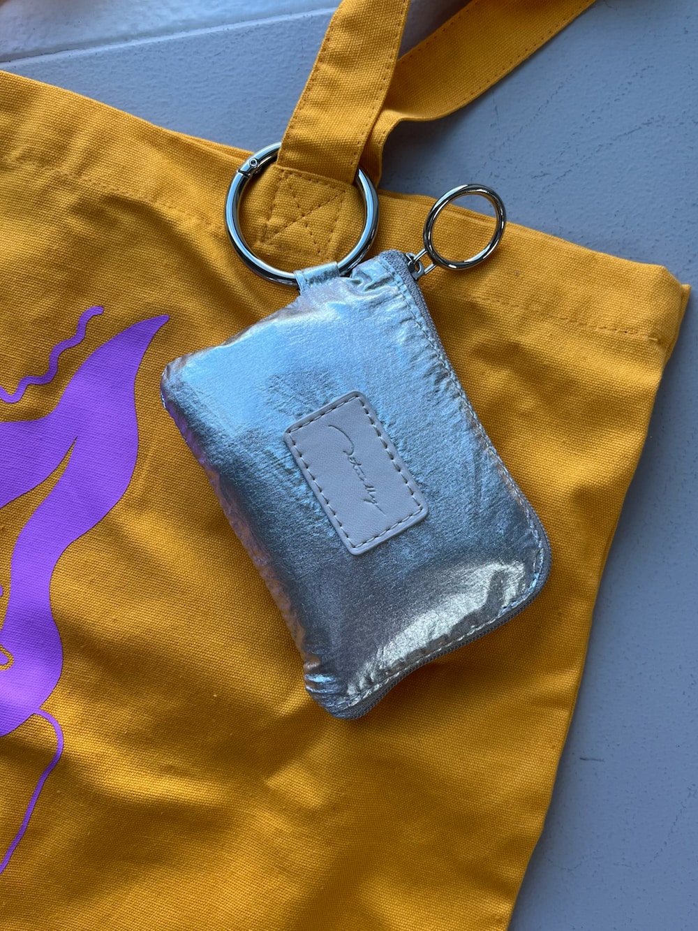 シルバー系のエコバッグ/サブバッグ、ブルー系のパスポートケース、グリーン系の財布を着用したレディースの夏コーディネートの4枚目の写真