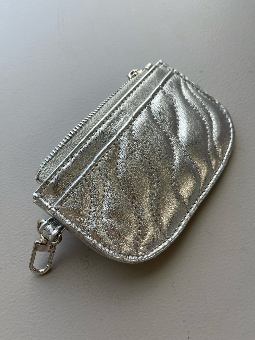 ホワイト系のスニーカー、シルバー系の財布、シルバー系のパスケースを着用したレディースの春コーディネートの3枚目の写真