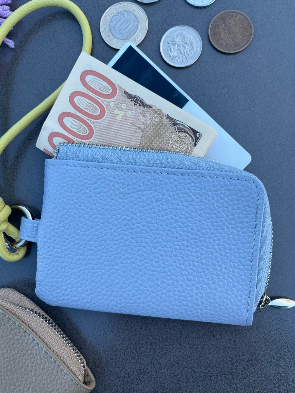 パープル系のポーチ、ベージュ系の財布、ブルー系の財布を着用したレディースの春コーディネートの2枚目の写真