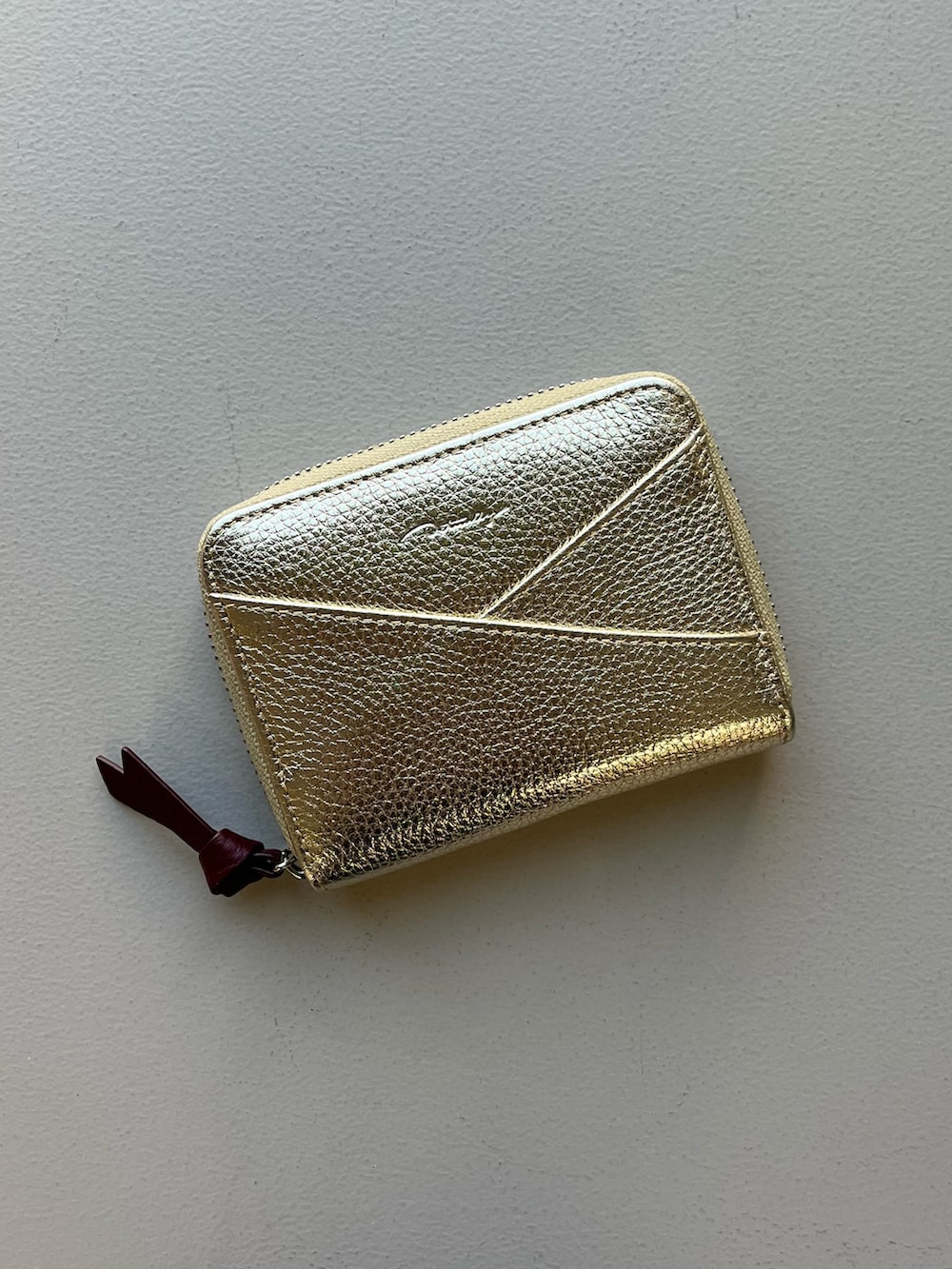 ゴールド系の財布、グリーン系のポーチ、ブルー系のチャームを着用したレディースの冬コーディネートの2枚目の写真