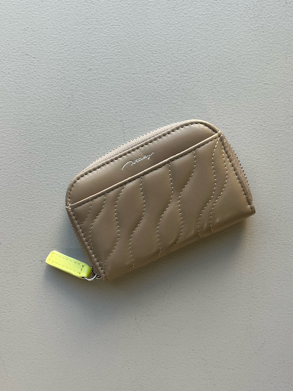 シルバー系の財布、ベージュ系のカードケース、グリーン系のポーチを着用したレディースの冬コーディネートの2枚目の写真