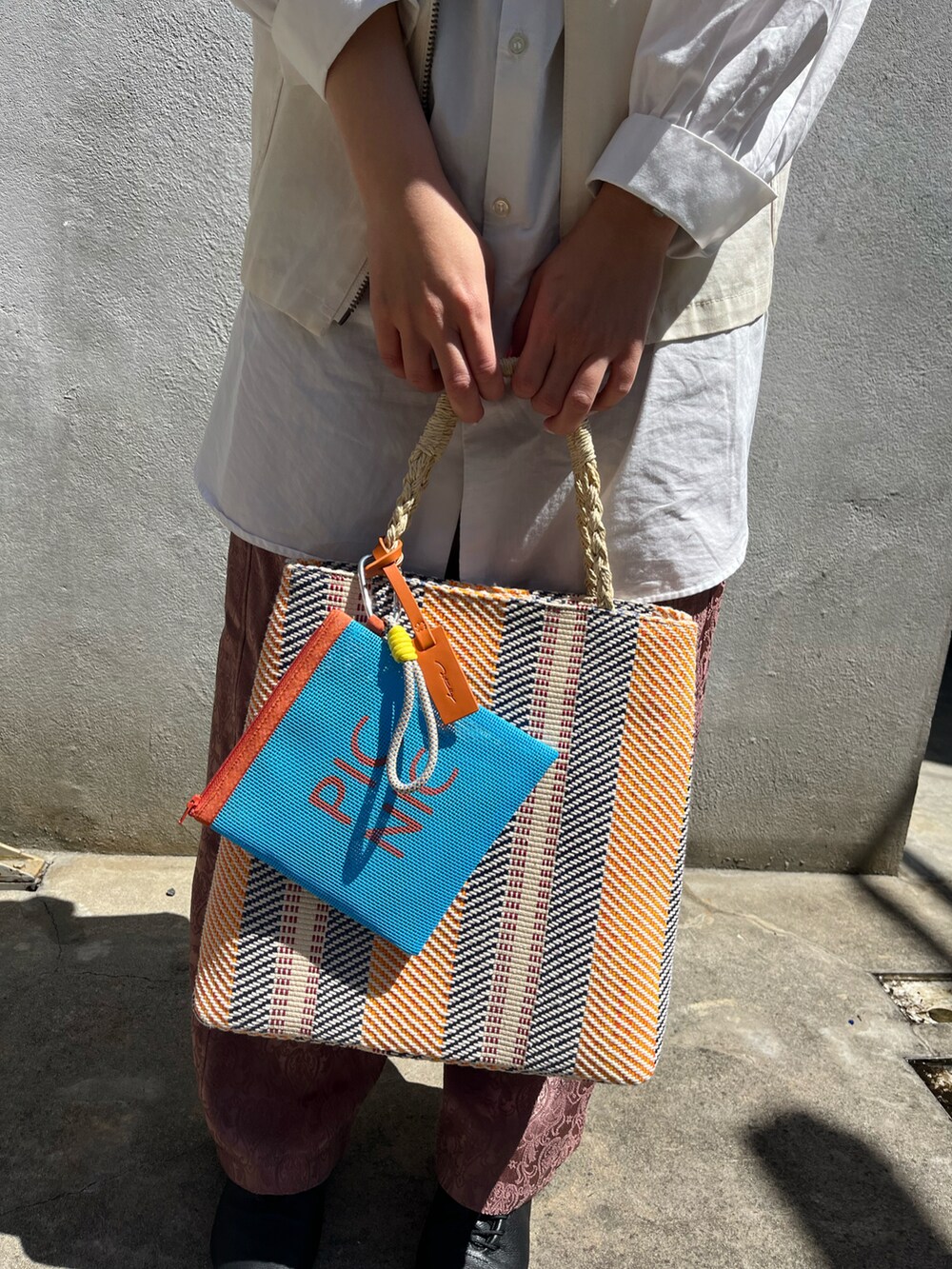 ブラック系のドレスシューズ、オレンジ系のトートバッグ、ホワイト系のシャツ/ブラウスを着用したレディースの春コーディネートの2枚目の写真