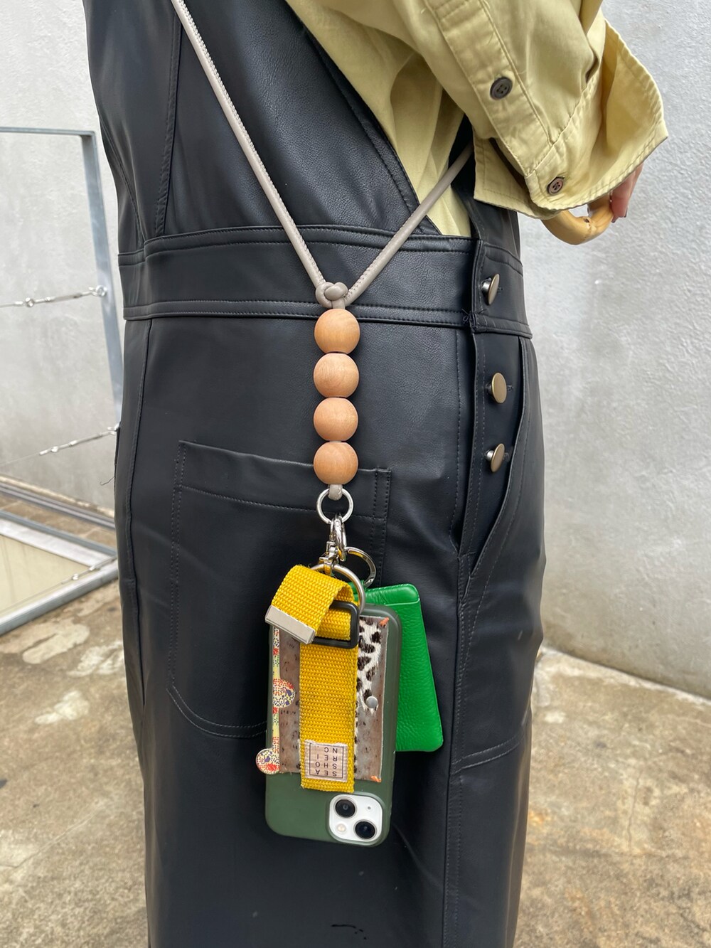 ホワイト系のスニーカー、ブラック系のジャンパースカート、グリーン系のシャツ/ブラウスを着用したレディースの春コーディネートの3枚目の写真