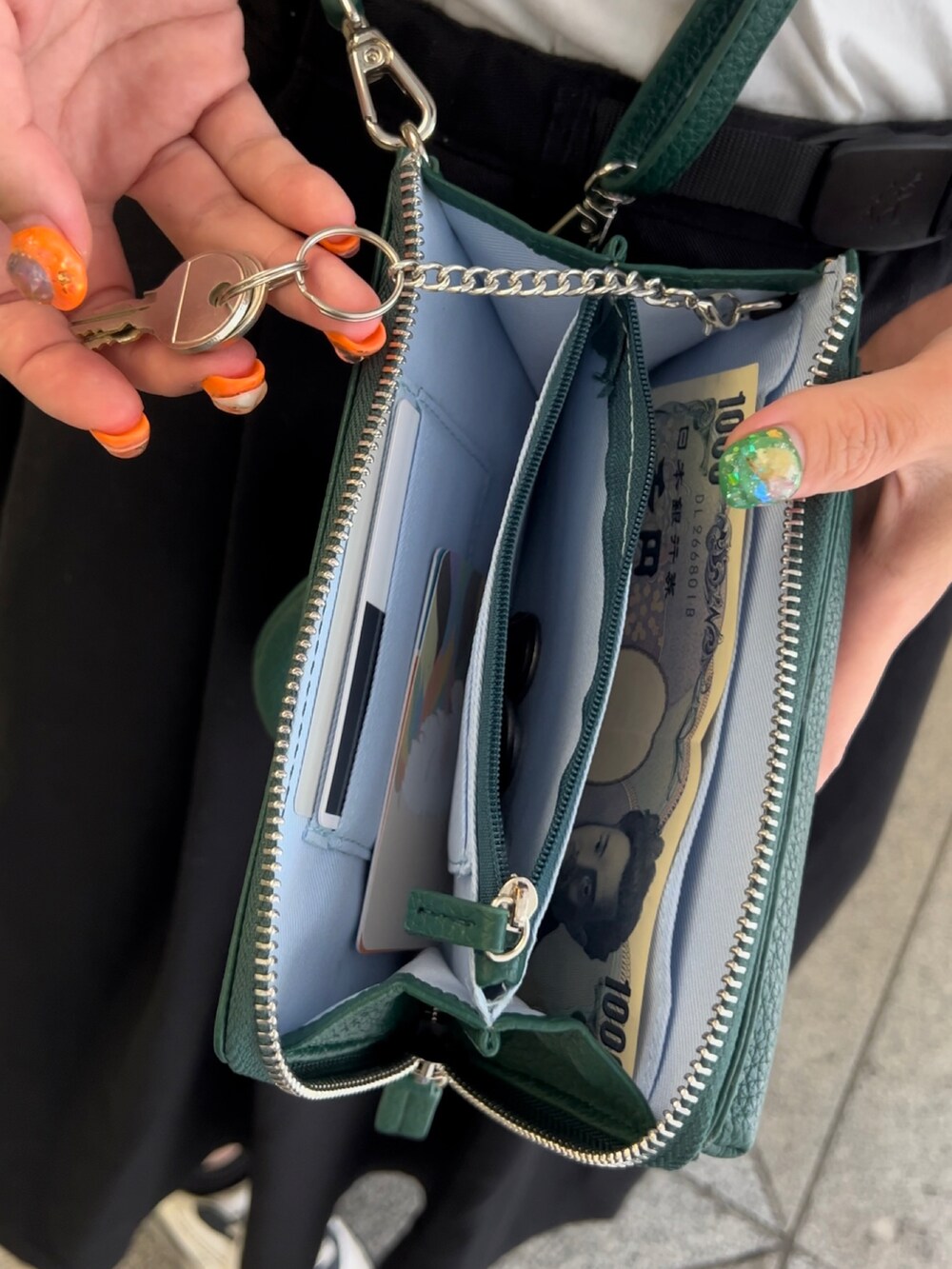 グリーン系のショルダーバッグ、ホワイト系のスニーカー、ブラック系のスカートを着用したレディースの夏コーディネートの2枚目の写真