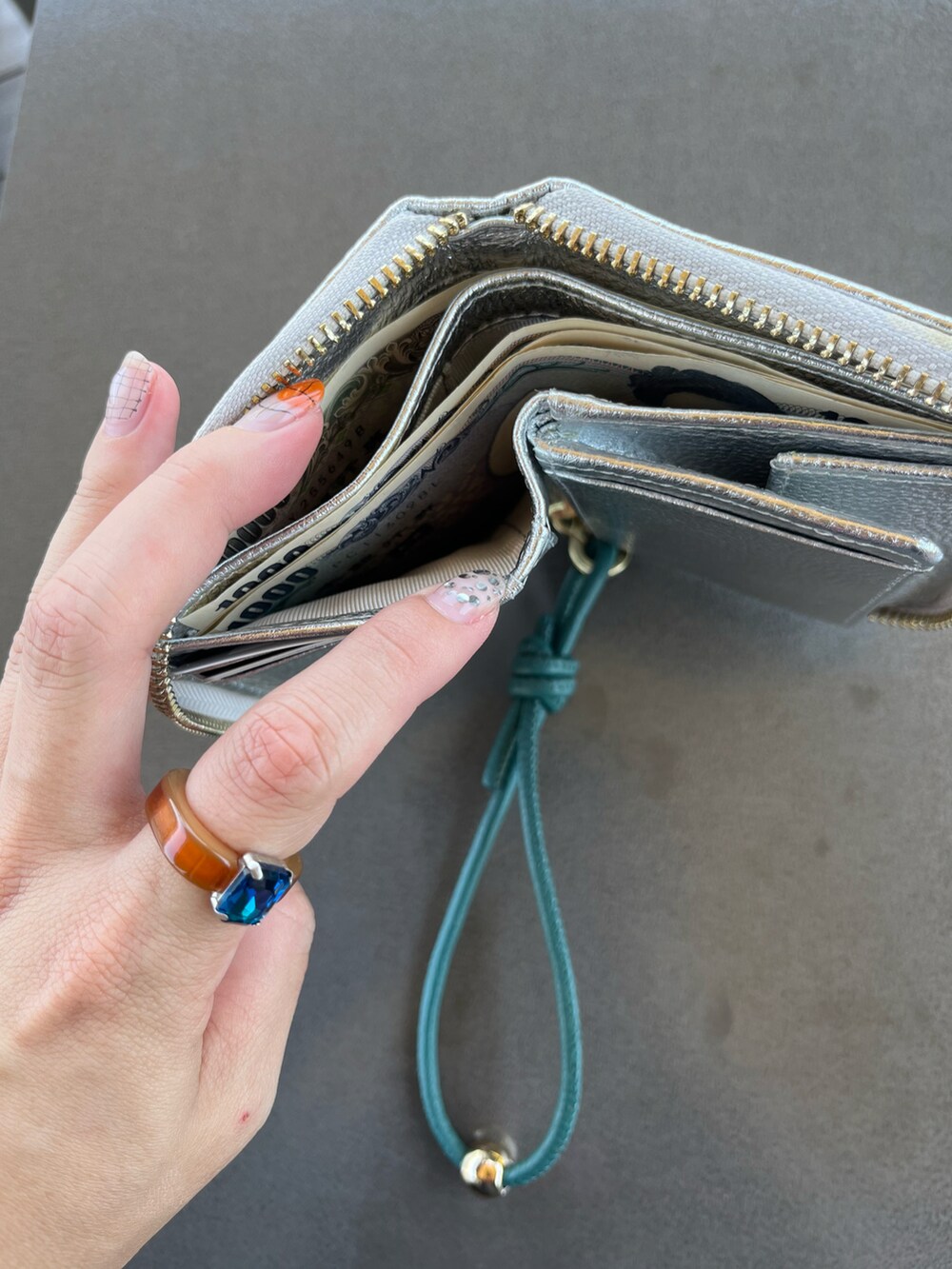 シルバー系のショルダーバッグ、グレー系のヘッドフォン/イヤホン、シルバー系の財布を着用したレディースの夏コーディネートの2枚目の写真