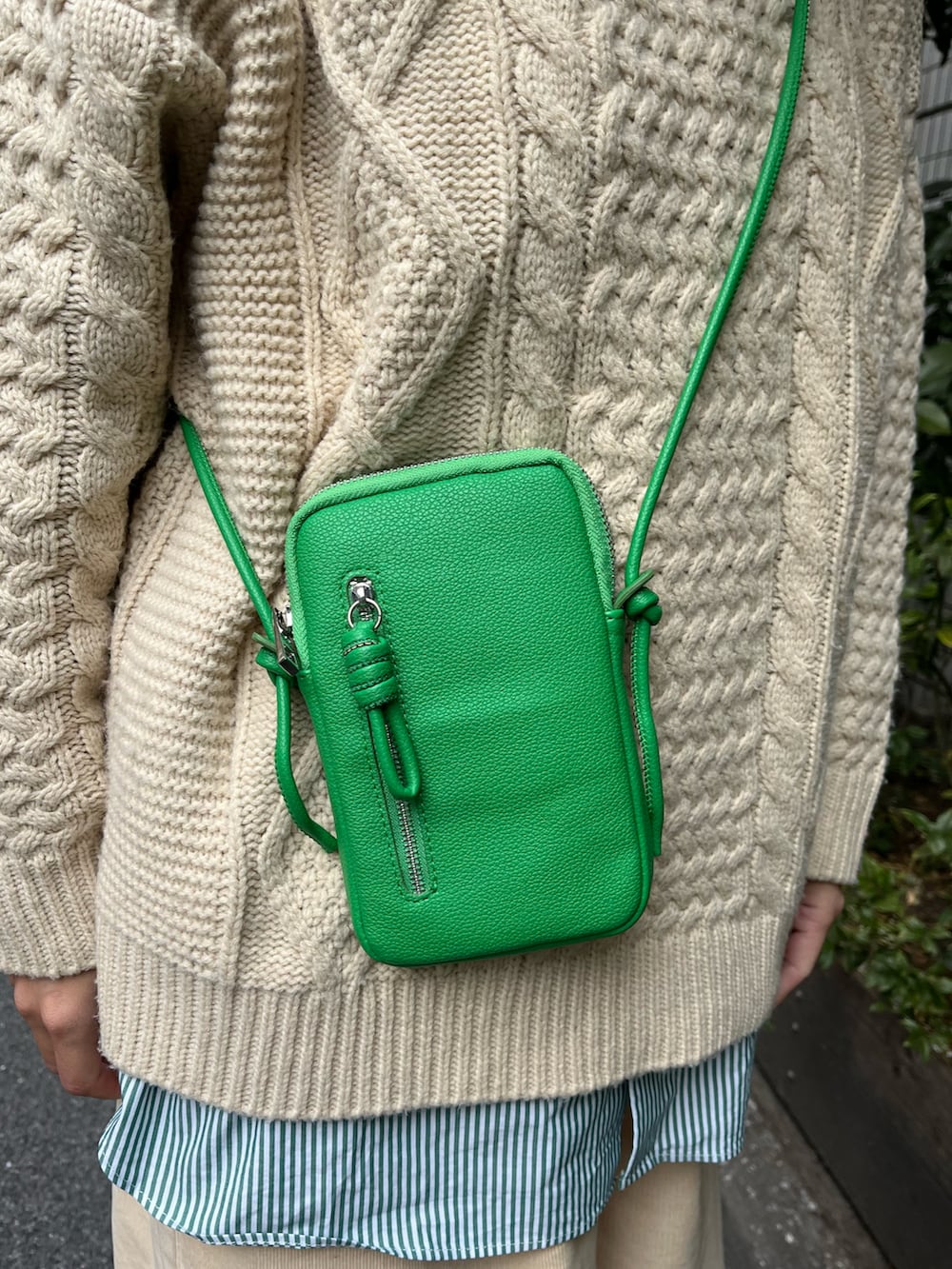 グリーン系のショルダーバッグ、ホワイト系のスニーカー、ベージュ系のニット/セーターを着用したレディースの冬コーディネートの3枚目の写真