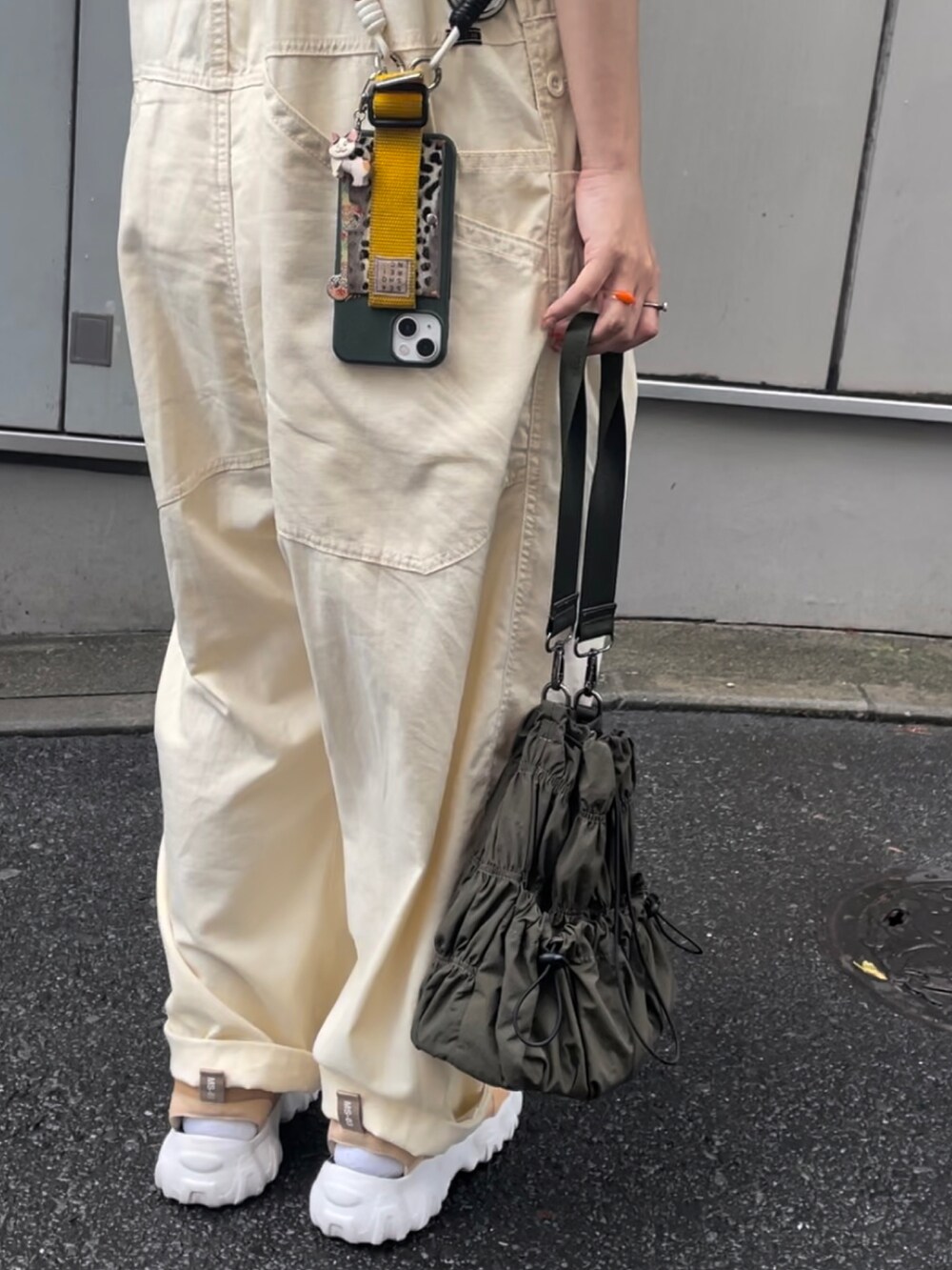 ベージュ系のスニーカー、グリーン系のトートバッグ、ベージュ系のサロペット/オーバーオールを着用したレディースの夏コーディネートの2枚目の写真