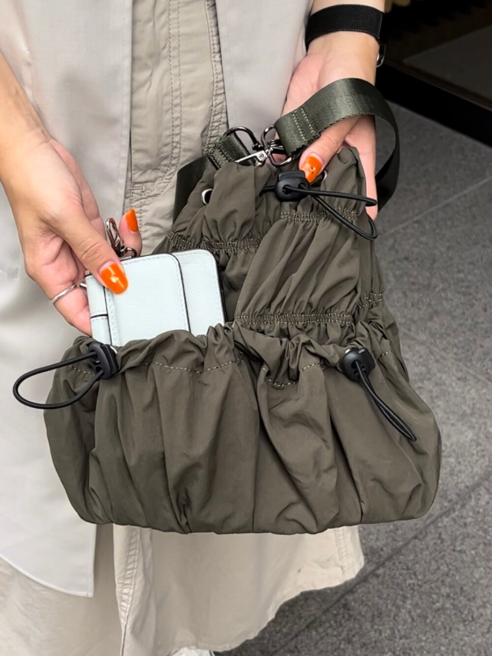 グリーン系のトートバッグ、ホワイト系のスニーカー、ブルー系の財布を着用したレディースの夏コーディネートの2枚目の写真