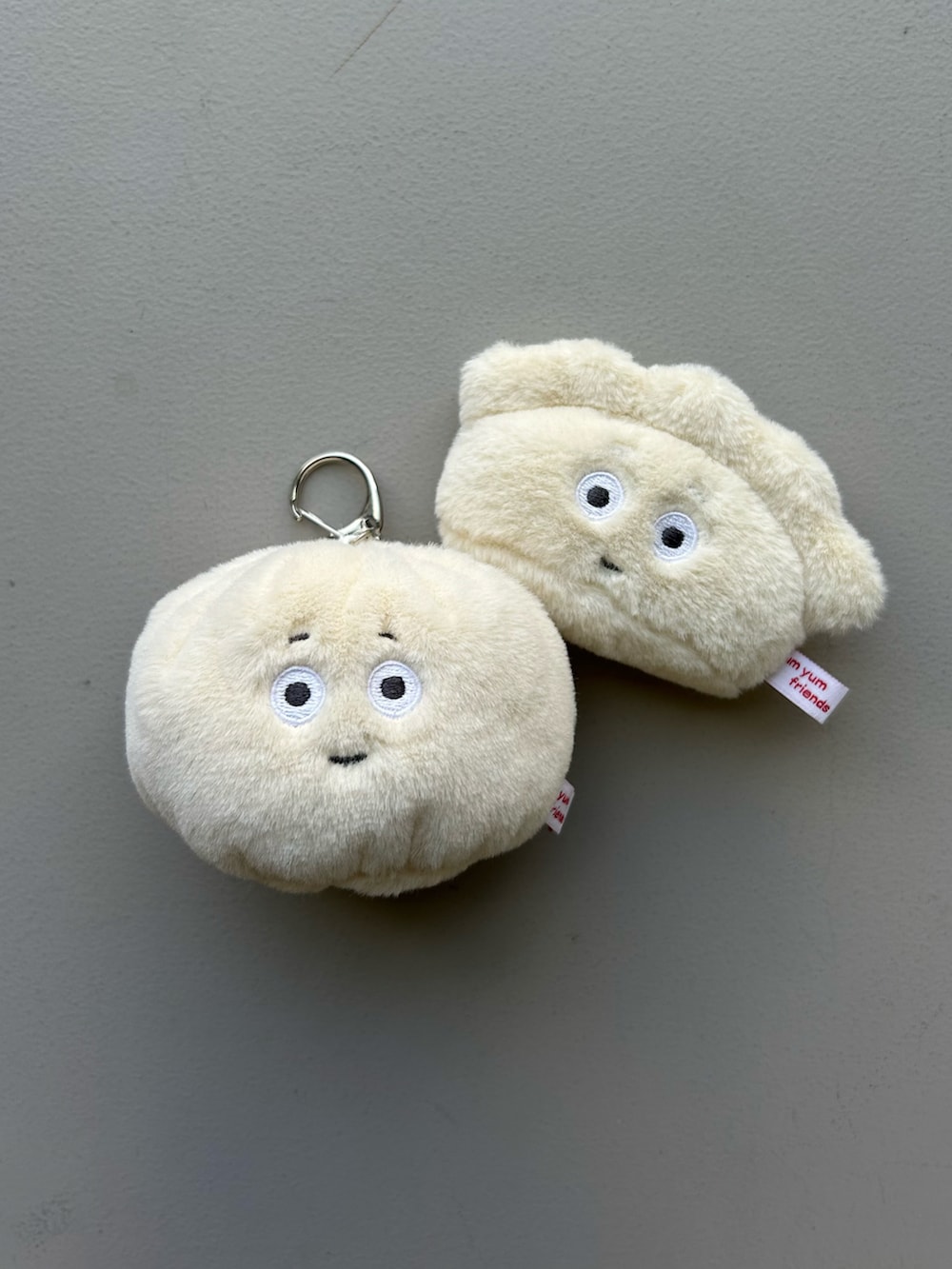 オレンジ系のポーチ、ホワイト系のチャーム、グレー系のポーチを着用したレディースの春コーディネートの4枚目の写真