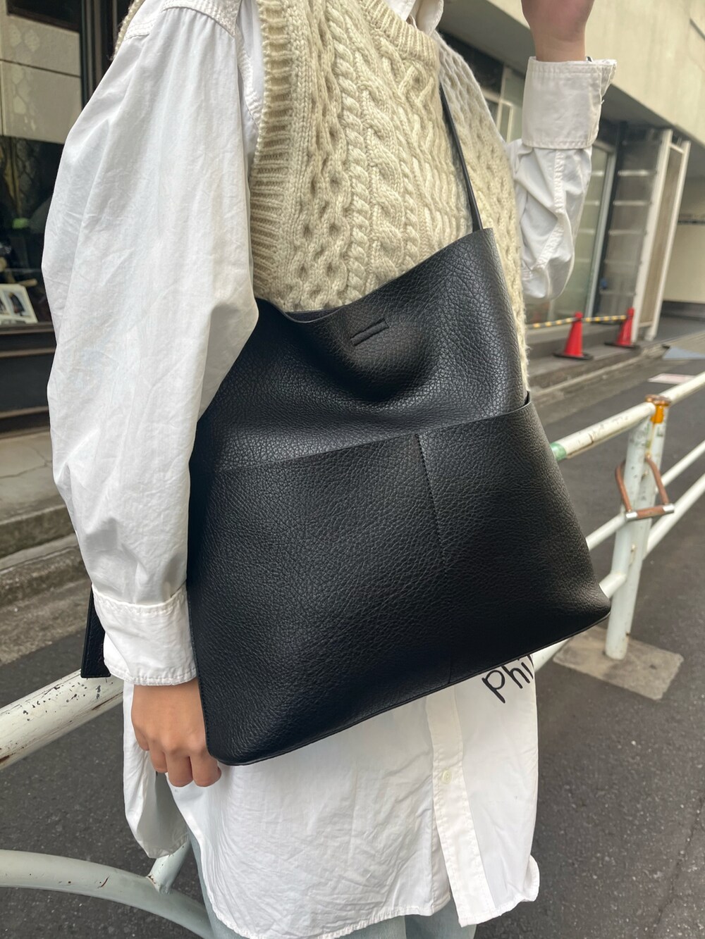 ブラック系のショルダーバッグ、ホワイト系のワンピース、ホワイト系のベストを着用したレディースの冬コーディネートの3枚目の写真