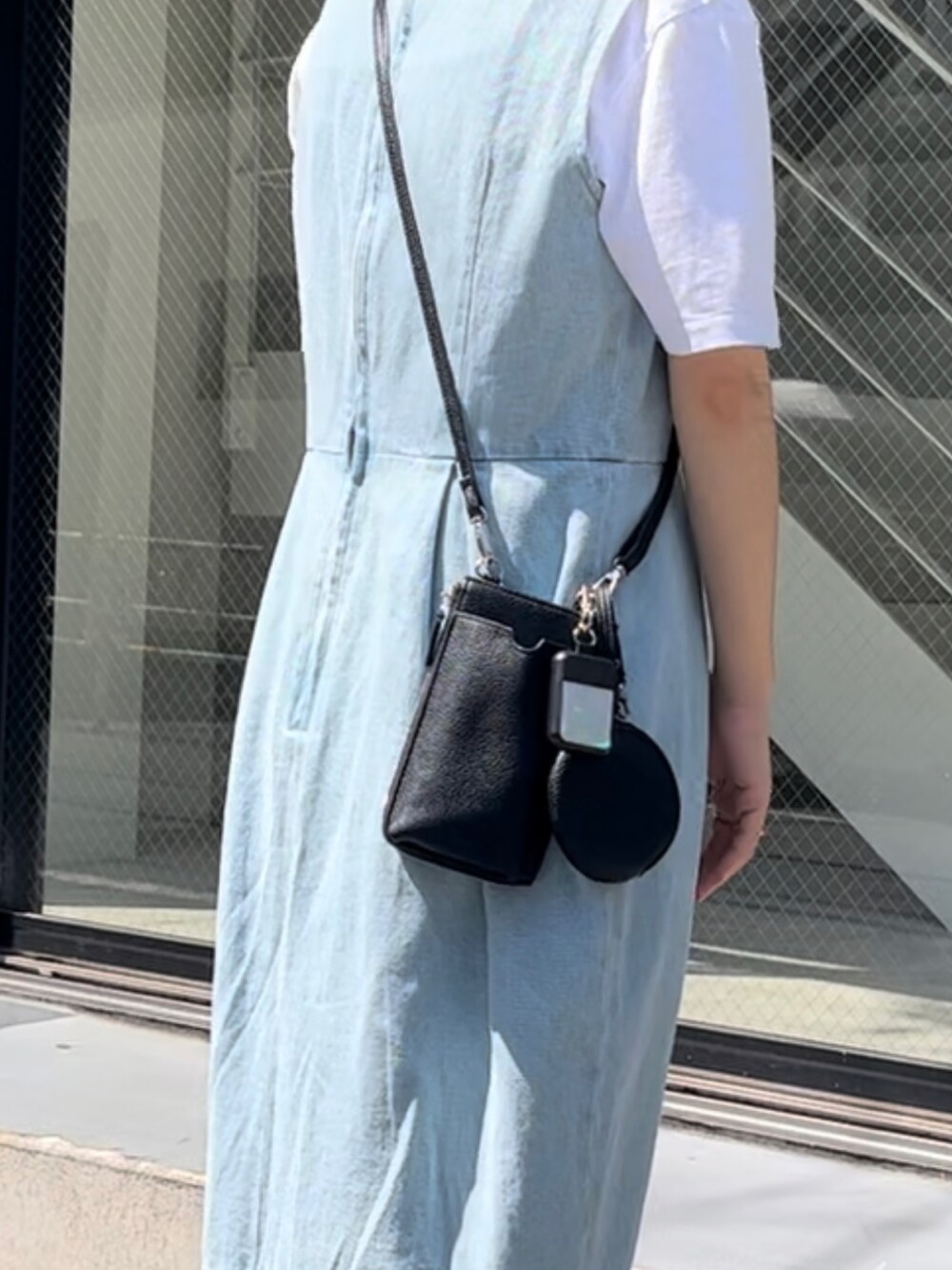 ホワイト系のスニーカー、ブラック系のショルダーバッグ、その他のスマホグッズを着用したレディースの夏コーディネートの2枚目の写真