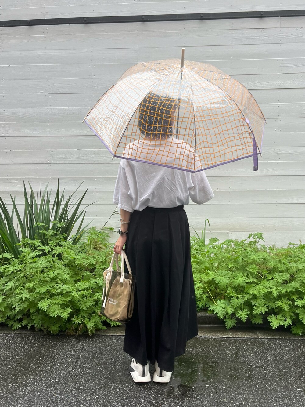 ブラック系のトートバッグ、ホワイト系のスニーカー、ホワイト系のTシャツ/カットソーを着用したレディースの夏コーディネートの2枚目の写真