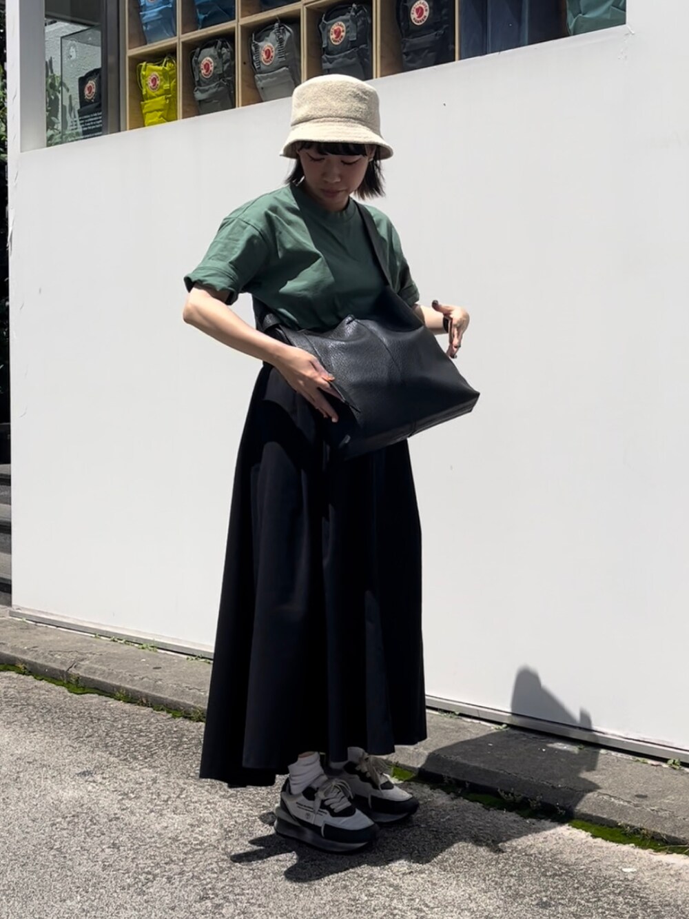 ブラック系のショルダーバッグ、ホワイト系のスニーカー、ベージュ系のスカートを着用したレディースの夏コーディネートの2枚目の写真