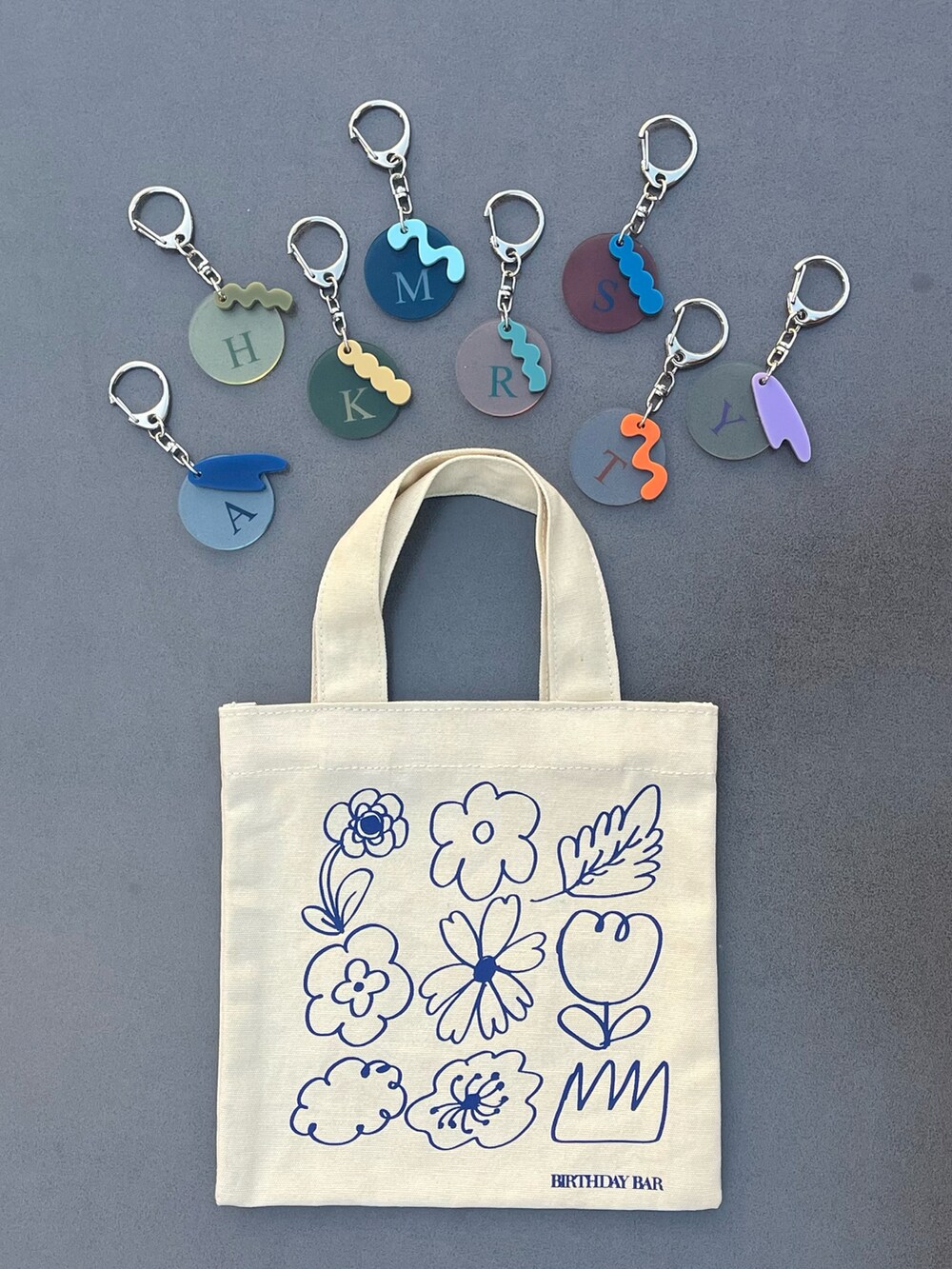 ホワイト系のトートバッグ、ブラック系のチャーム、グレー系のチャームを着用したレディースの春コーディネートの3枚目の写真