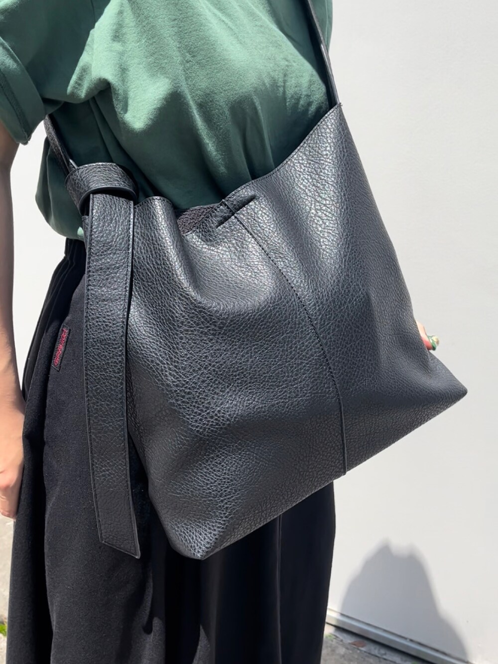 ブラック系のショルダーバッグ、ホワイト系のスニーカー、ベージュ系のスカートを着用したレディースの夏コーディネートの3枚目の写真