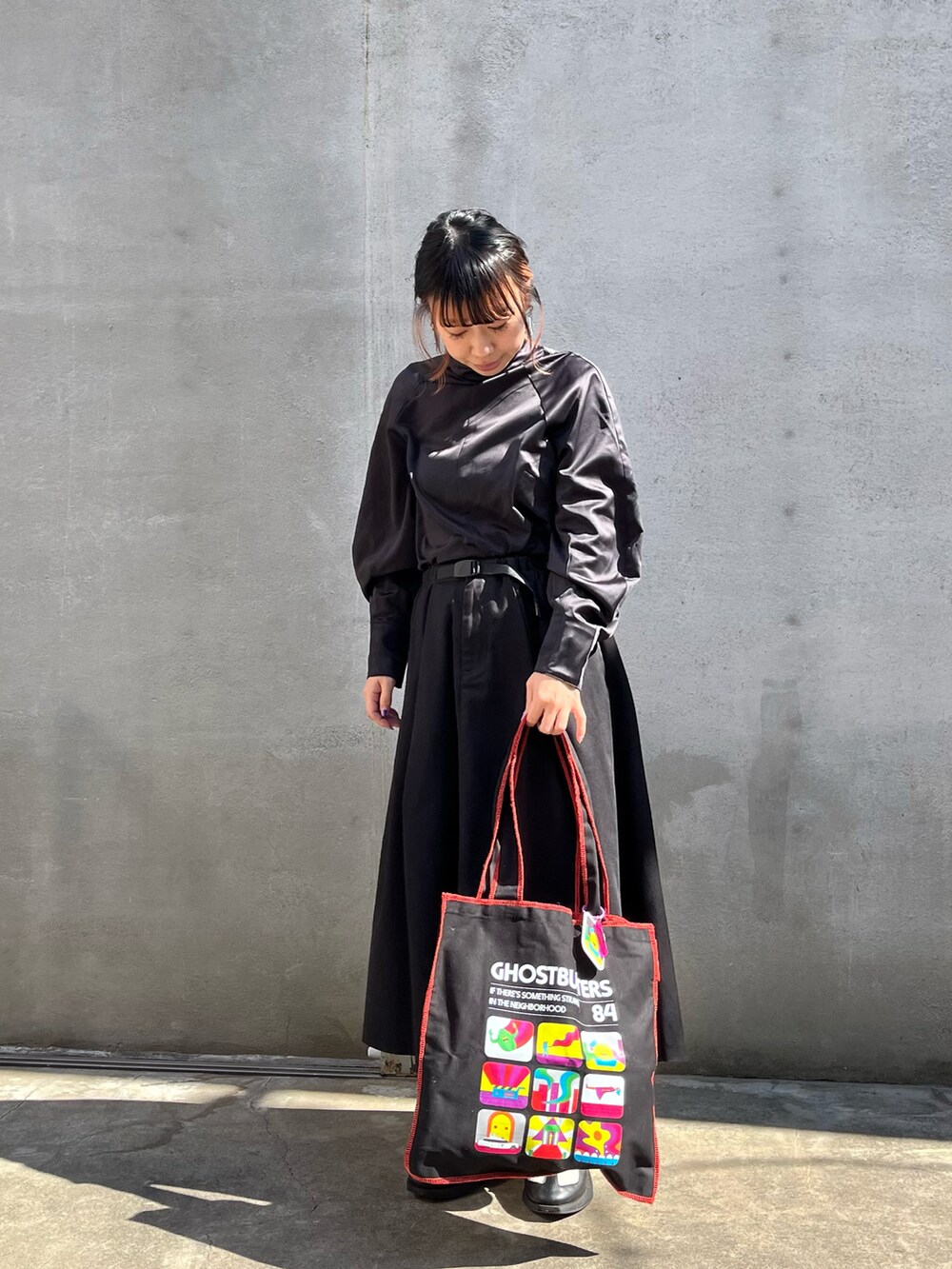 ホワイト系のスニーカー、ブラック系のスカート、ブラック系のトートバッグを着用したレディースの春コーディネートの2枚目の写真